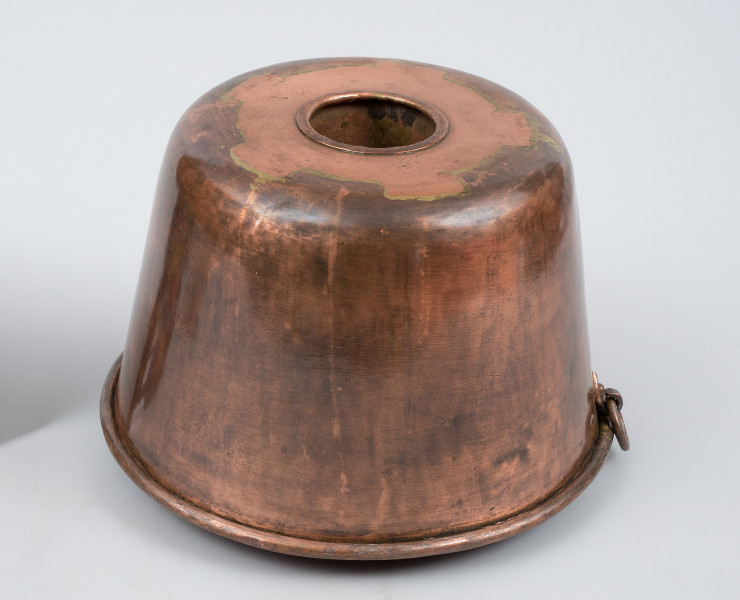 ujęcie 3/4 z góry. Naczynie w kształcie lekko zwężającego się u góry walca, z wgłębieniem w kształcie tulei pośrodku.