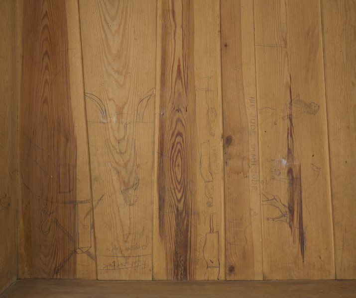 szafa - Szafa drewniana, dwudrzwiowa, w kolorze brązowym (kolor naturalnego drewna). Obiekt został z zewnątrz zabezpieczony lakierem. U dołu szafy widoczne dwie szuflady zamykane na klucz (brak kluczy; brak okucia zamka prawej szuflady). Wewnątrz, na tylnej ścianie, w jej górnej części umieszonych zostało siedem drewnianych wieszaków. W połowie wysokości zwieńczenia szafy widoczna pozioma listwa (ubytek listowy na prawej ścianie). Płyciny drzwi wykonane są z desek. Obiekt jest pozbawiony zdobień. Od spodu, w narożnikach szafy umieszczone zostały cztery podtrzymujące obiekt nogi wykonane z fragmentów deski i pomalowane żółto-brązową farbą olejną.W wnętrzu szafy, na tylnej ścianie oraz ścianach bocznych widoczne napisy oraz rysunki wykonane odręcznie ołówkiem. Na lewej ścianie widoczny napis: „Ta szafa była moi mieszkaniem ukrywalnym dn 21 II 43 r do dnia 25 IIII 43 r”, wizerunek nagiej kobiety stojącej bokiem i trzymającej ręce na kroczu (zasłaniającej się) oraz kobiety w kostiumie, której twarz jest ujęta z profilu, a jedna z nóg uniesiona do góry. Jej włosy są ułożone w fale. Pod nagą kobietą widniej podpis ,,(Głupia baba)’’. Nad kobietą w kostiumie napisano ,,(Francóska niewiasta)’’. Obok nagiej kobiety widoczna jest kolejna data: ,,20.1.43 r.’’.
Na tylnej ścianie widoczne są przedstawienia (od lewej strony): budynku mieszkalnego (domu jednorodzinnego),  wiatraka (pod nim), kobiety w spódnicy za kolano i kamizelce stojącej bokiem (obok, z prawej strony rysunku wiatraka), trzech postaci umieszczonych jedna pod drugą, niewielkiego samochodu (obok, z prawej strony postaci), drogowskazu (obok, z prawej strony samochodu), mężczyzny z długą brodą (Żyda; pod nim) ciągnącego za sobą konia oraz niedokończonej nagiej postaci przedstawionej tyłem (widoczne pośladki; pod rysunkiem konia).
Obok przedstawienia kobiety widoczny napis: ,,Hiszpańska dziewczyna’’. Pod spodem widoczny napis ,,Pffeferwehrtag | Przygody Tomcia | paluszki’’. Obok trzech postaci (ułożonych w linii jedna pod drugą) napis ,,(kąpiel)’’. Na drogowskazie napis ,,Do Palestyny 3814 km’’. Obok mężczyzny z brodą widoczny napis wersalikami „HIR, JUDE, DI, AŁH, JUDE’’.
Na prawej ścianie szafy widoczne przedstawienie zbliżenia cielesnego (dwóch nagich postaci połączonych ze sobą w uścisku), które zostało częściowo starte.
Wszystkie rysunki widoczne na ścianach bocznych zostały wykonane z boku zwrócone są górą do tylnej ściany obiektu. Rysunki widoczne na tylnej ścianie obiektu usytuowane są do góry nogami (odwrócone o 180° w stosunku do dna szafy).