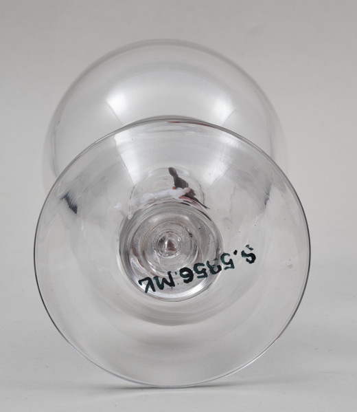 ﻿Kielich w typie „Römer”. Posiada półkolistą czaszę z cylindrycznym zwężeniem u góry. Charakterystyczny jest nodus w kształcie kuli. Kielich zakończony jest okrągłą, gładką stopą. Stopa i czara połączone są z nodusem pierścieniami. W nodus wtopiona jest scena myśliwska.