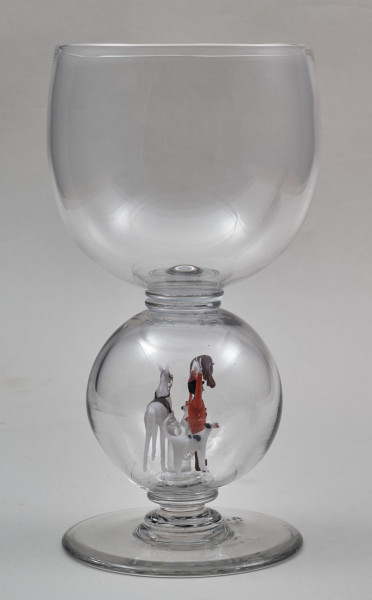 ﻿Kielich w typie „Römer”. Posiada półkolistą czaszę z cylindrycznym zwężeniem u góry. Charakterystyczny jest nodus w kształcie kuli. Kielich zakończony jest okrągłą, gładką stopą. Stopa i czara połączone są z nodusem pierścieniami. W nodus wtopiona jest scena myśliwska.