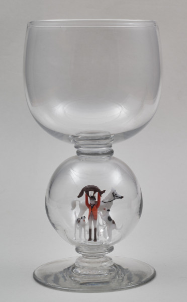 ﻿Kielich w typie „Römer”. Posiada półkolistą czaszę z cylindrycznym zwężeniem u góry. Charakterystyczny jest nodus w kształcie kuli. Kielich zakończony jest okrągłą, gładką stopą. Stopa i czara połączone są z nodusem pierścieniami. W nodus wtopiona jest scena myśliwska.