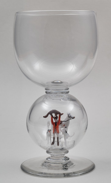 ﻿Kielich w typie „Römer”. Posiada półkolistą czaszę z cylindrycznym zwężeniem u góry. Charakterystyczny jest nodus w kształcie kuli. Kielich zakończony jest okrągłą, gładką stopą. Stopa i czara połączone są z nodusem pierścieniami. W nodus wtopiona jest scena myśliwska.