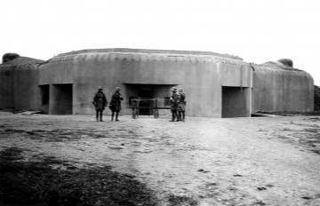 MZŁ-DRM-1901/48 Zdjęcie ukazuje czterech żołnierzy stojacych przed bunkrem.
Mężczyźni są umundurowani w kurtki skórzane, wysokie buty i hełmy.