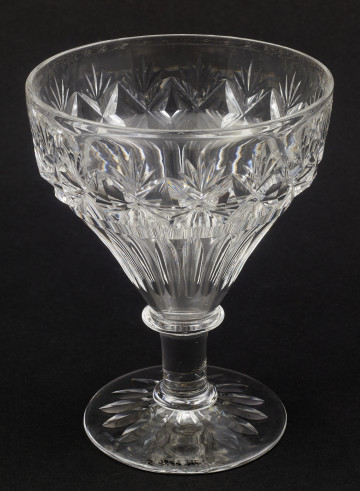 Kieliszek okrągły, ozdobiono szlifowaną dekoracją rośliną. Stopa okrągła, nóżka krótka i szeroka, zakończona pierścieniem, na którym osadzona stożkowata czara. Spód stopy dekorowany płytkim szlifem o motywie wielopłatkowego kwiatka.