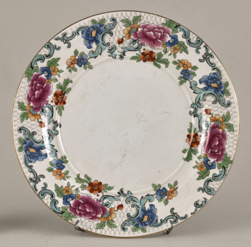 Mały, płytki talerzyk wykonany z białego fajansu. Stanowi podstawkę pod sosjerkę